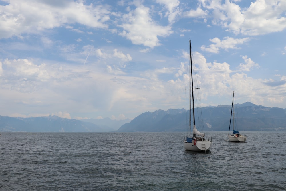 two sailboats in the water with mountains in the background