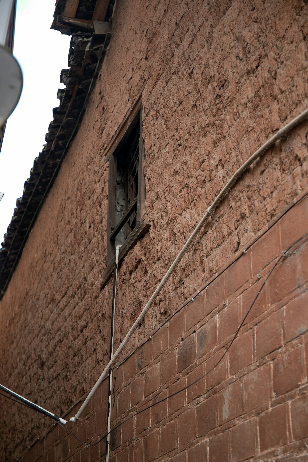 Un edificio de ladrillo rojo con una ventana y un alambre a un lado