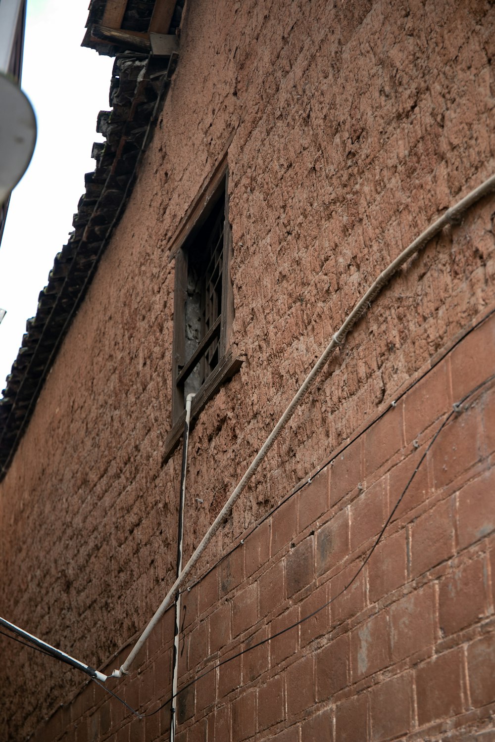 a red brick building with a window and a wire on the side of it