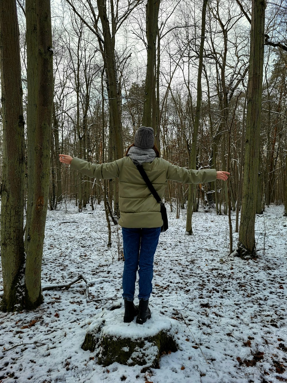 a woman standing in the woods with her arms outstretched