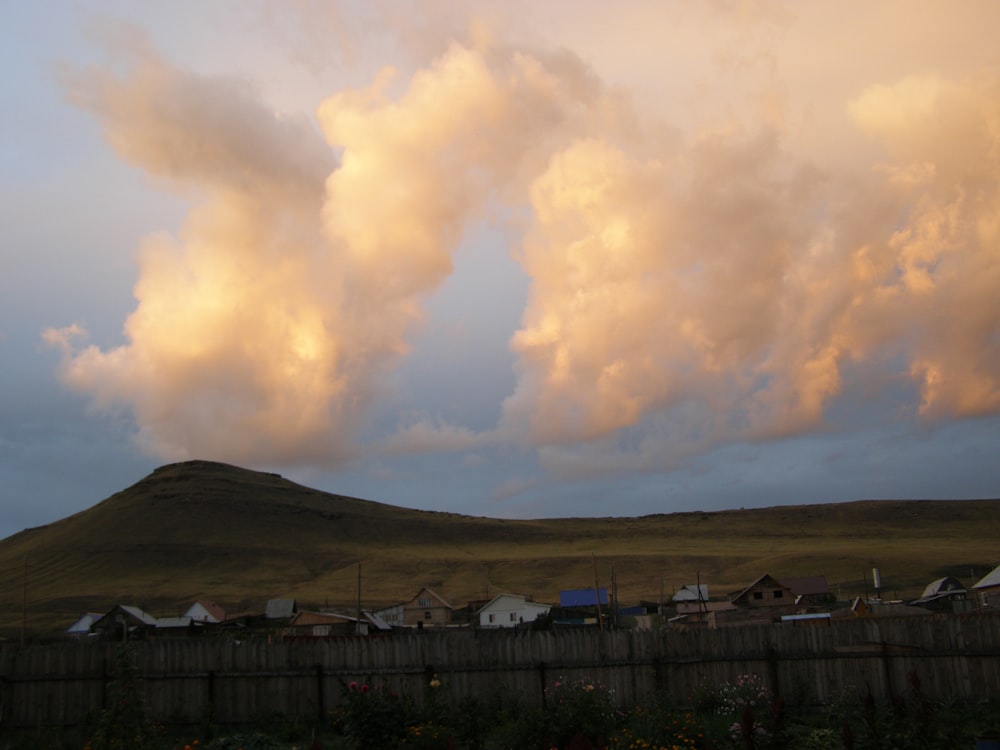 a cloudy sky over a small town with a mountain in the background