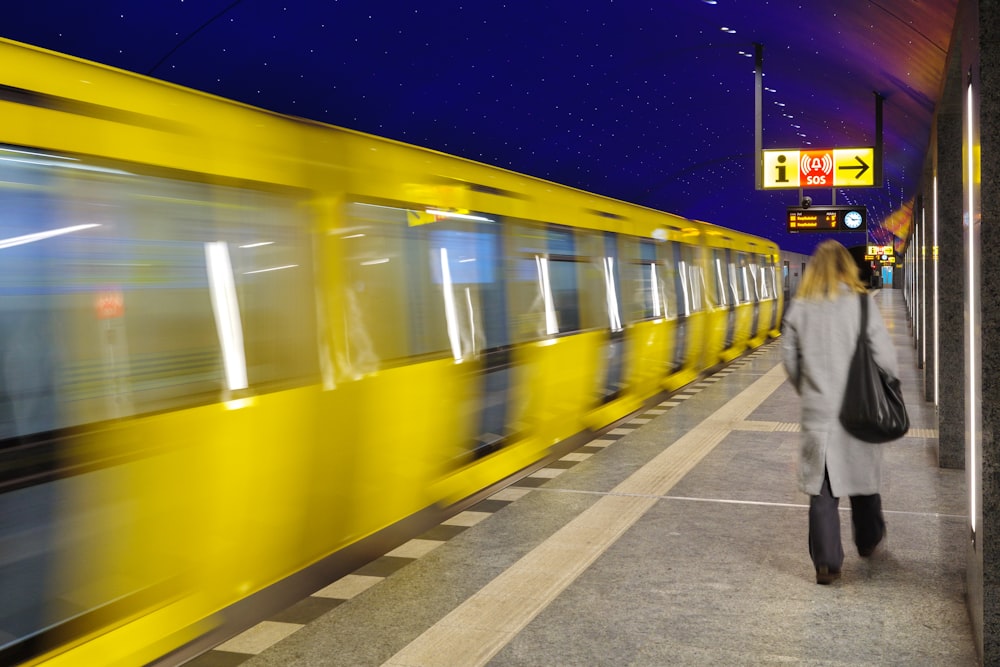 a woman walking on a platform next to a train