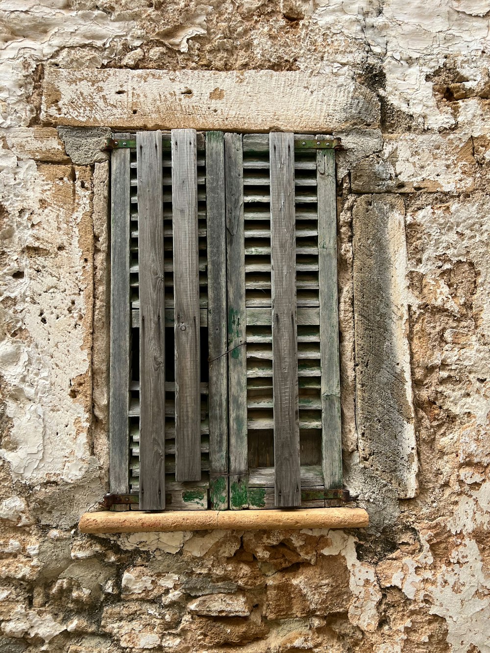 una ventana con postigos de madera sobre una pared de piedra