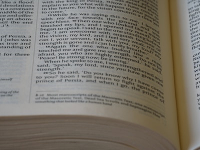 The photo captures a close-up view of an open book with visible text on its pages. The text appears to be from a religious or philosophical book, as it contains numbered verses and references to visions and dialogues. The focus is on the middle right section of the right page, with words printed in a clear, serif font. The background includes a blurred portion of the book's spine and other pages.