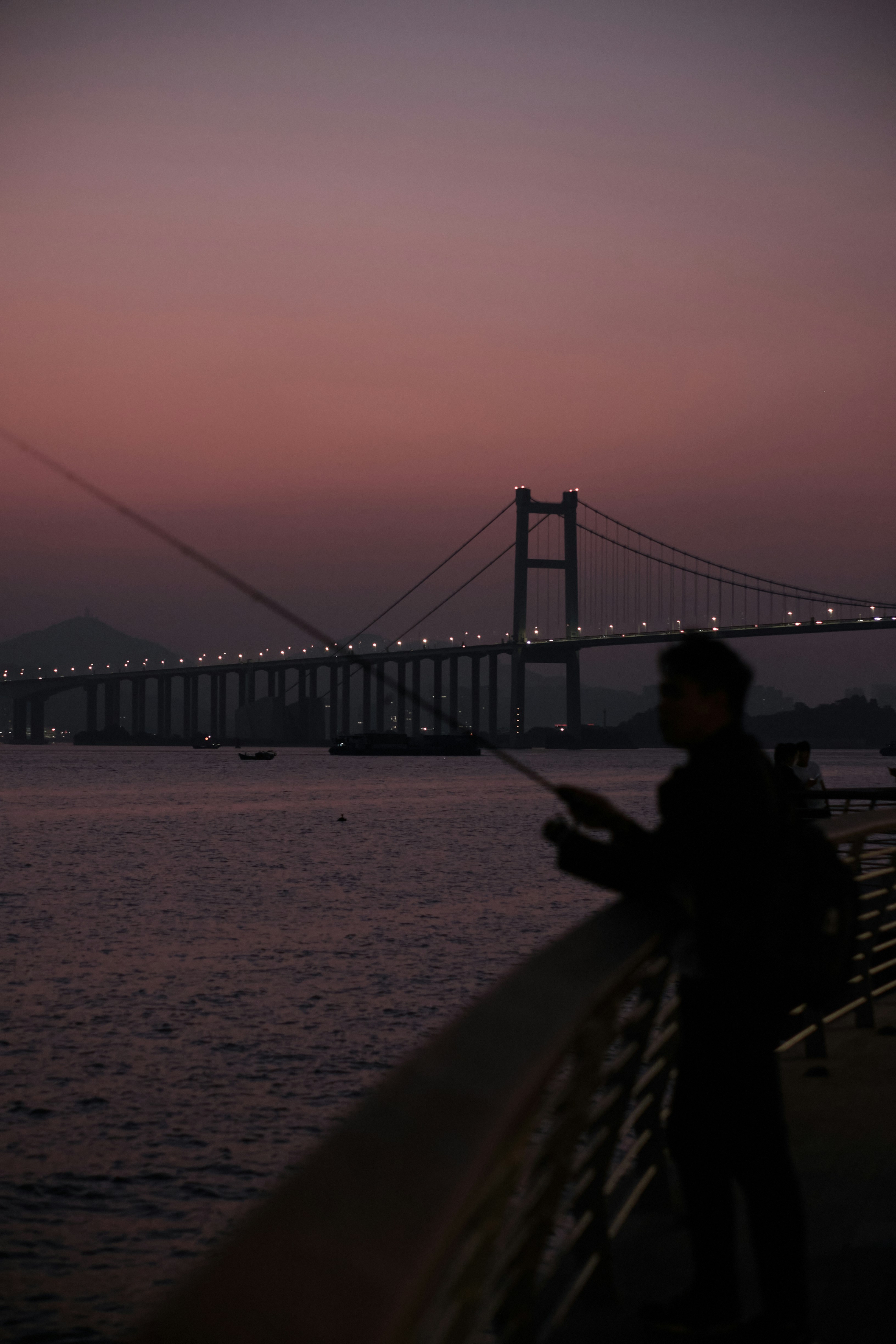 a man standing next to a body of water near a bridge