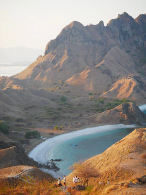 Tourists hiking a scenic trail along the coastline of Santiago island with turquoise waters.