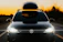 A sleek black Toyota Voxy parked outside a modern airport terminal under golden evening light.