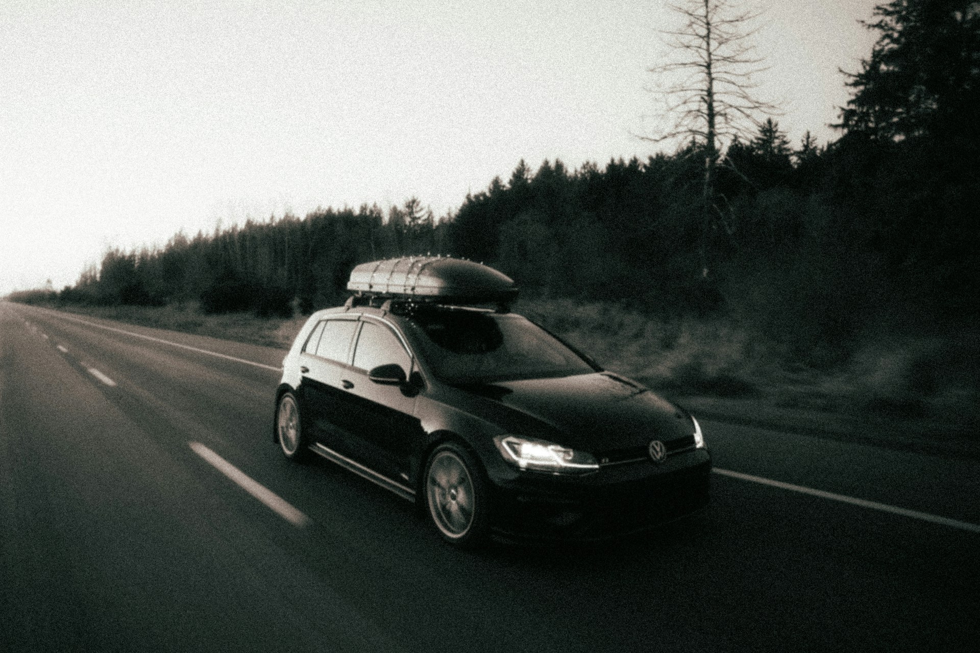 a car driving down a road with a surfboard on top of it