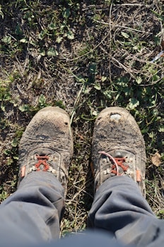 A pair of sturdy hiking boots dusted with trail dirt on a rocky path.