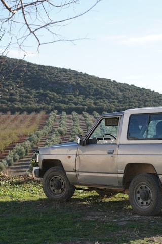 A compact autonomous rover navigating through lush green agricultural fields under a clear sky.