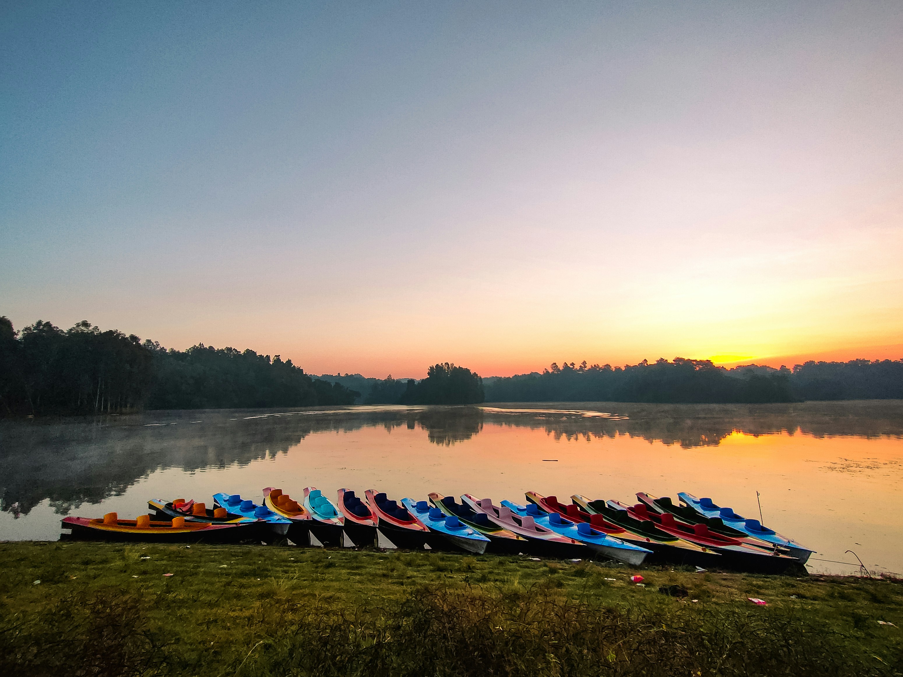 a row of canoes sitting on the shore of a lake