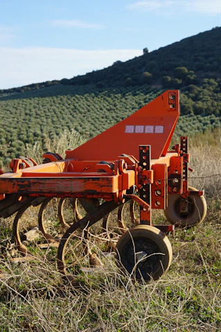 a red plow sitting on top of a lush green field