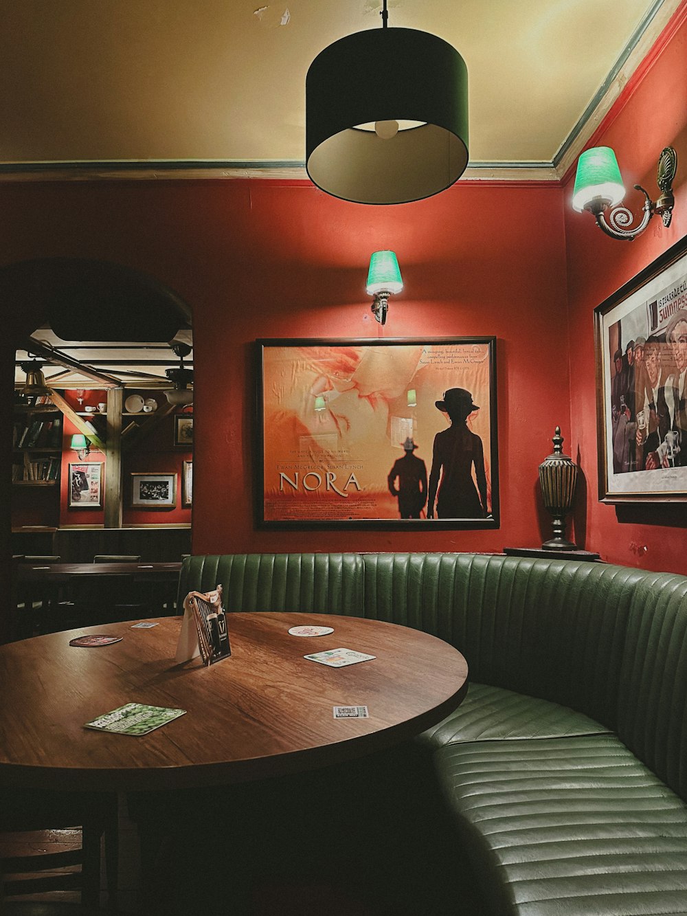 a booth with a round wooden table and a green bench