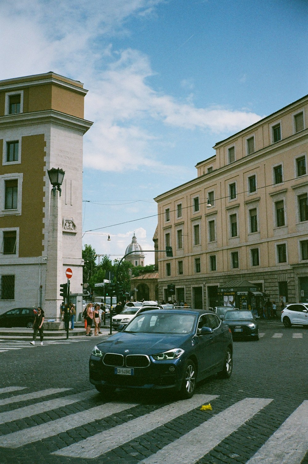 a black car driving down a street next to tall buildings