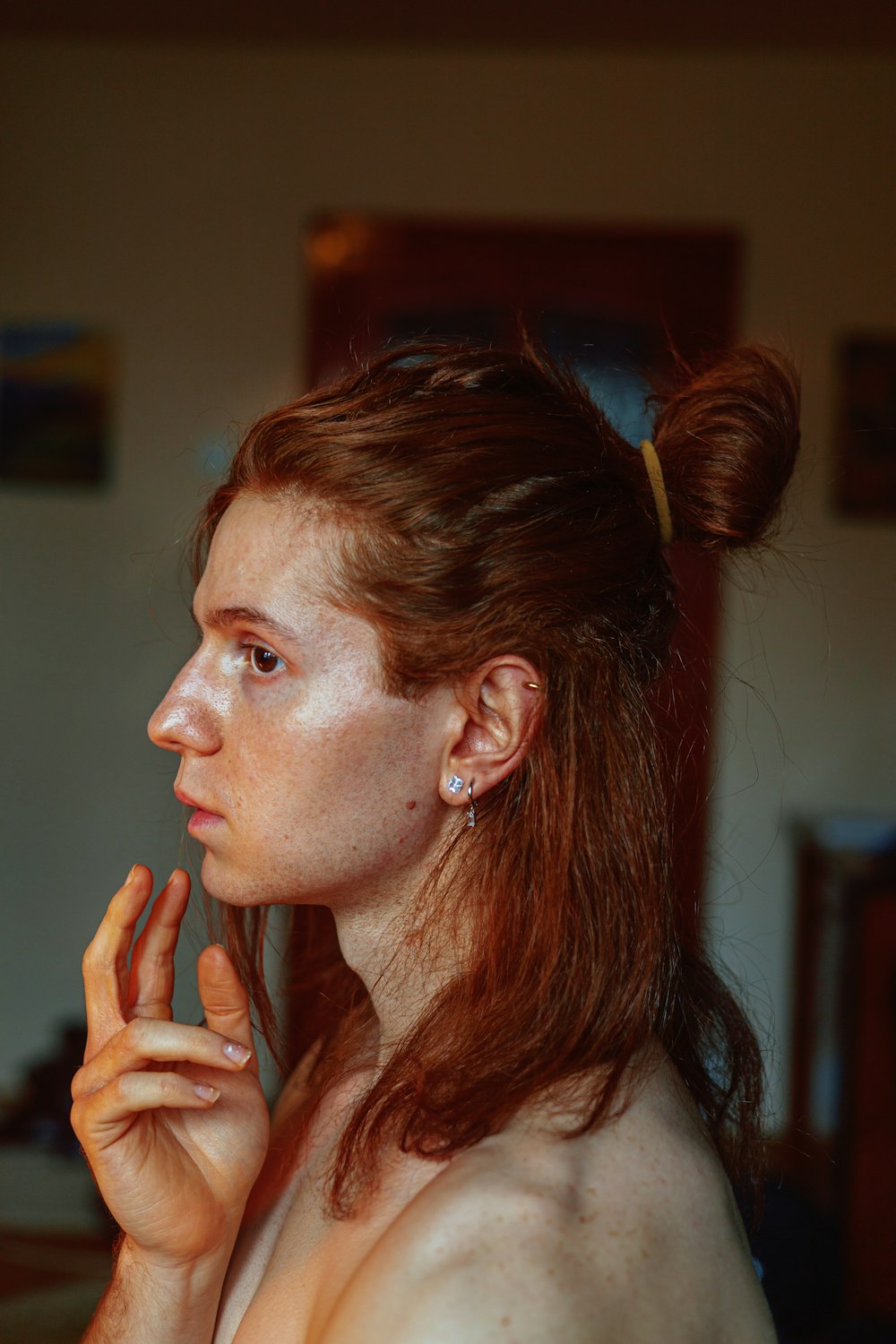 a woman with freckled hair is holding her hand up to her face