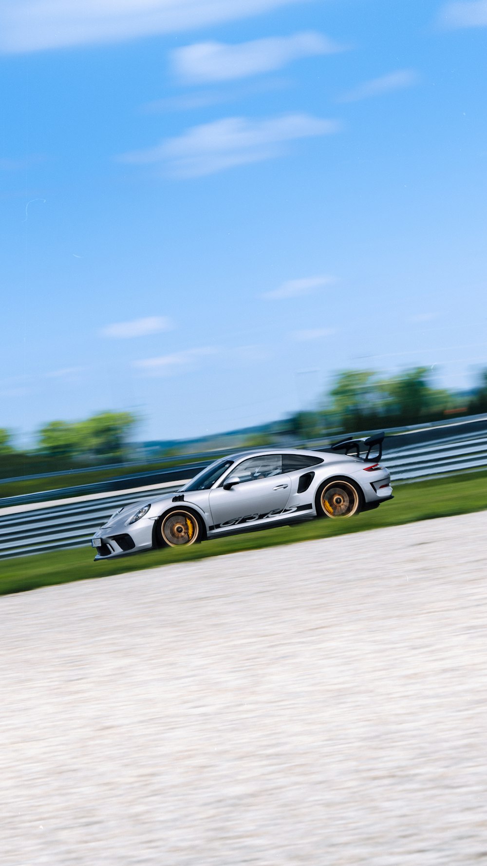 a silver sports car driving down a race track