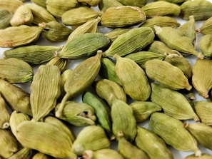 a pile of green seeds on a white surface