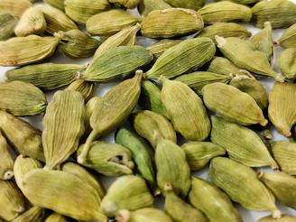 a pile of green seeds on a white surface