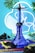 A blue hookah with geometric patterns sits in the center, surrounded by green leaves. It is placed on a colorful mat with 'CHIMBEROS' text. Black charcoal cubes are scattered around, and a mustache-shaped accessory is also present. The background features neon blue and white light in a circular design.