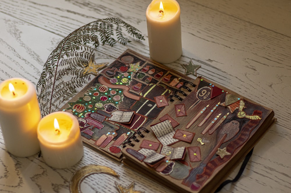 Três velas são acesas ao lado de um livro sobre uma mesa