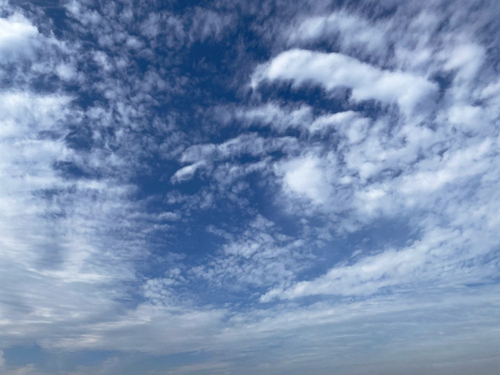 a person standing on a beach with a surfboard under a cloudy blue sky