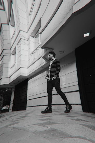 A fashionable person wearing oversized sunglasses walking confidently down a city street on a sunny day.