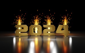 Golden numbers '2024' are displayed prominently against a dark background. Behind the numbers, bright and vibrant fireworks burst upwards, casting a warm glow and reflection on the surface below.