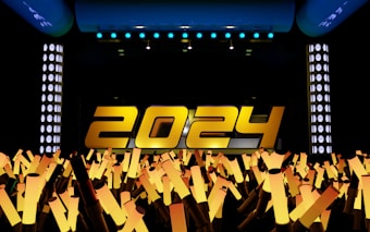 Large yellow numbers spelling out '2024' are prominently displayed on a stage with bright lights. Below the numbers, a crowd of illuminated light sticks points upward, creating a celebratory atmosphere.