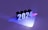The image consists of the number 2024 in bold, three-dimensional text that seems to be illuminated by colorful lights. The background is a rich purple hue with blue and pink lighting effects casting shadows and reflections on the surface.