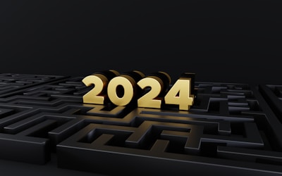 Golden numbers spelling out 2024 sit on top of a dark, intricate maze. The lighting highlights the numbers, creating a striking contrast with the black background.