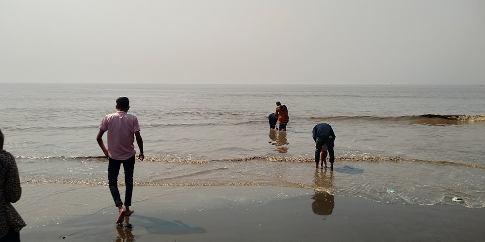 a group of people standing on top of a beach next to the ocean