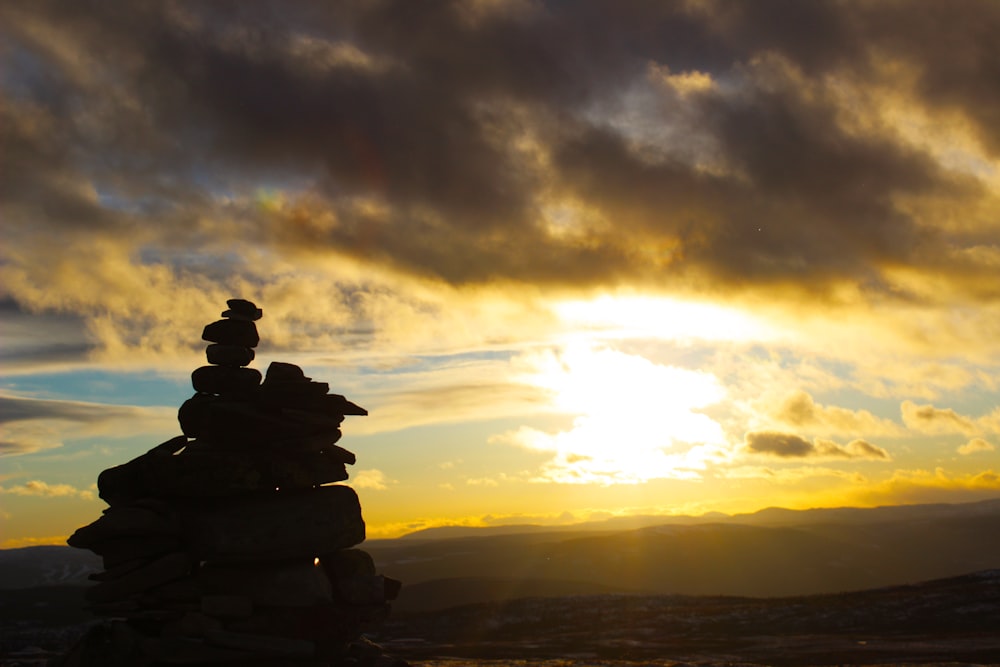 a stack of rocks sitting on top of a hill under a cloudy sky