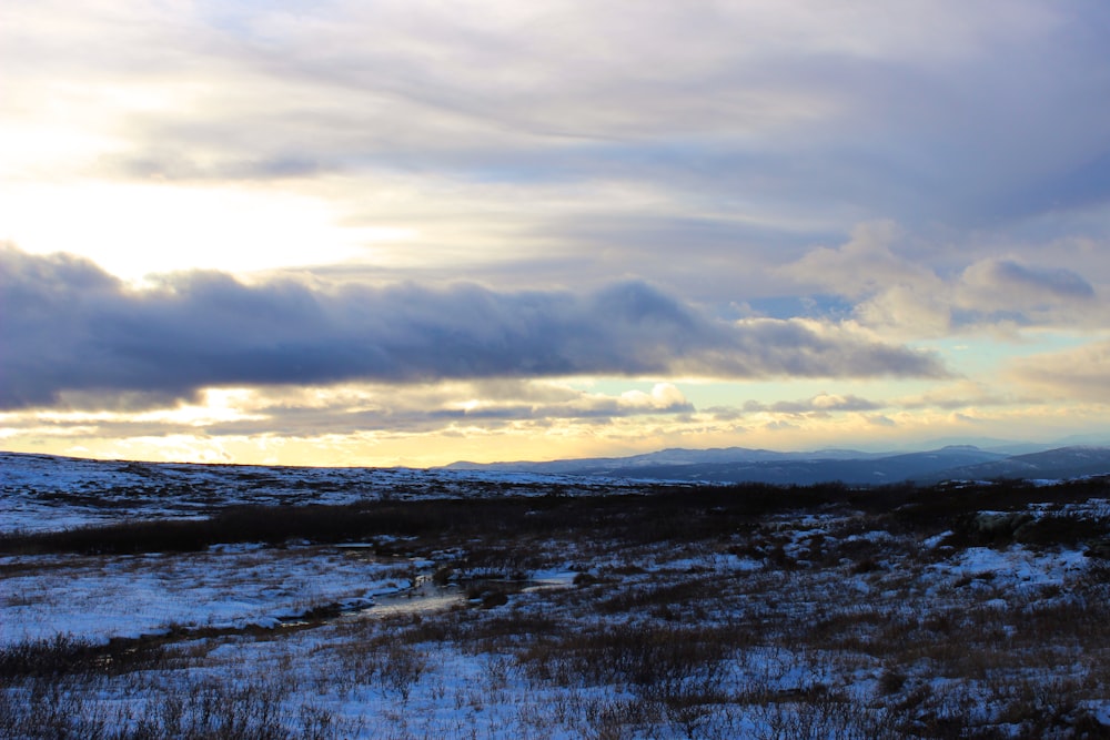 the sun is shining through the clouds over a snowy field