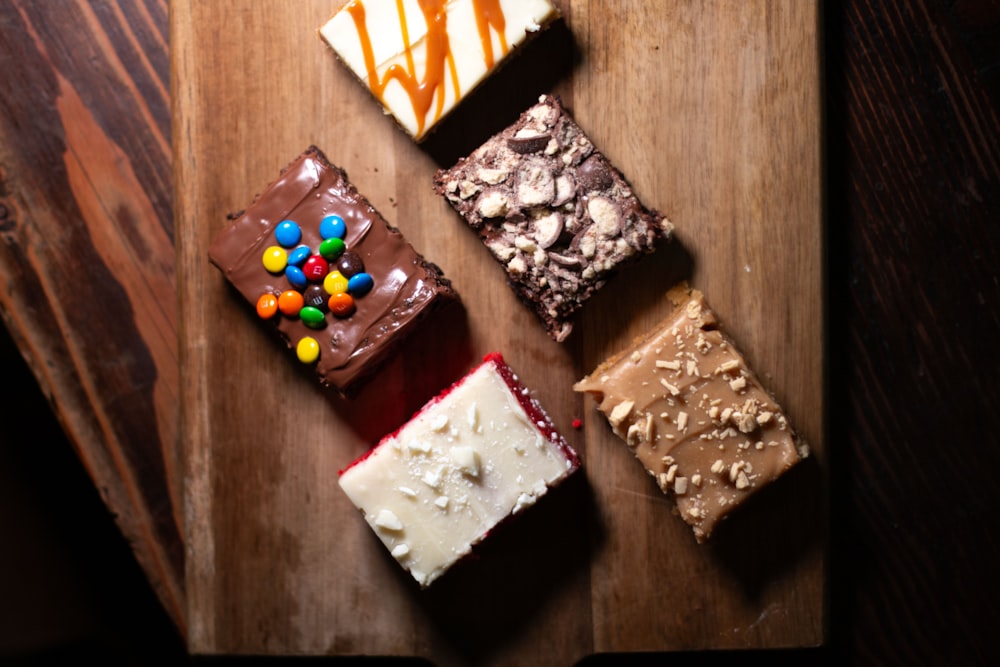 a wooden cutting board topped with different types of desserts