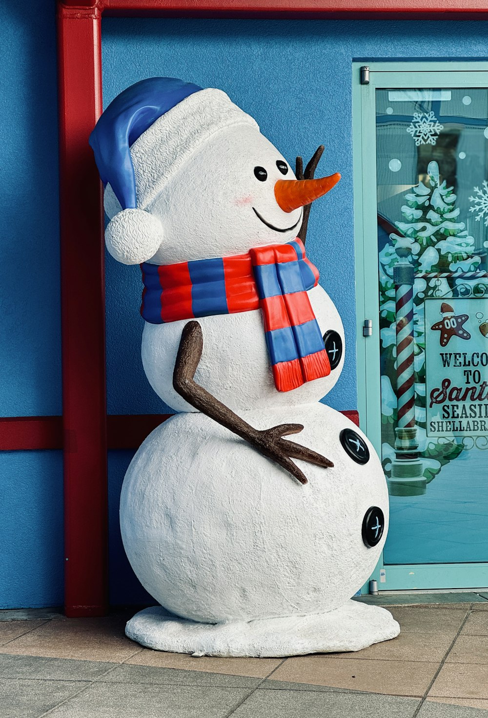 a snowman statue in front of a blue building