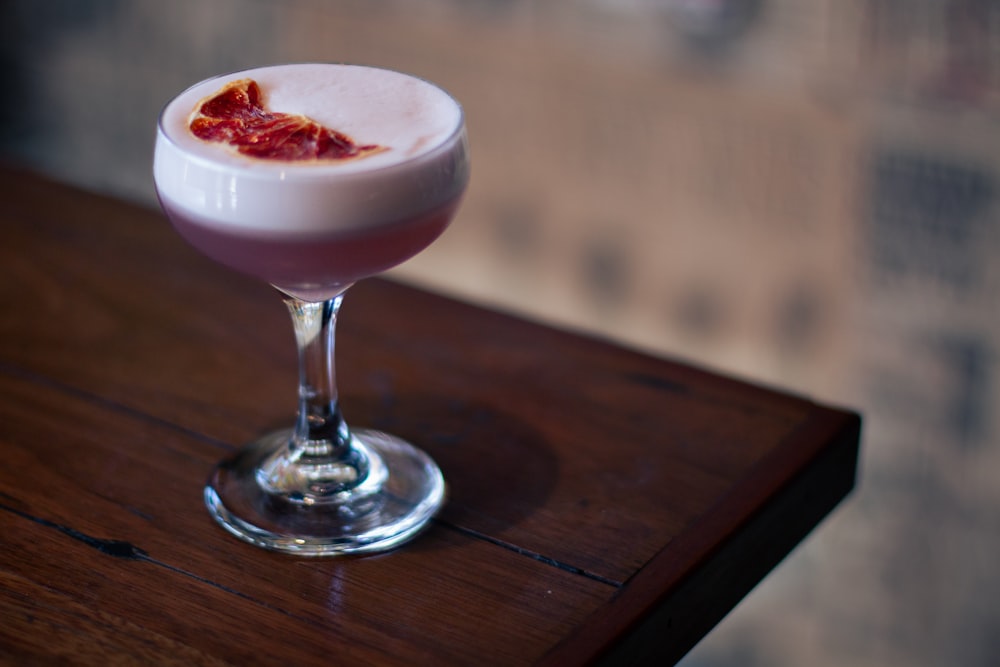 a small glass filled with a drink on top of a wooden table