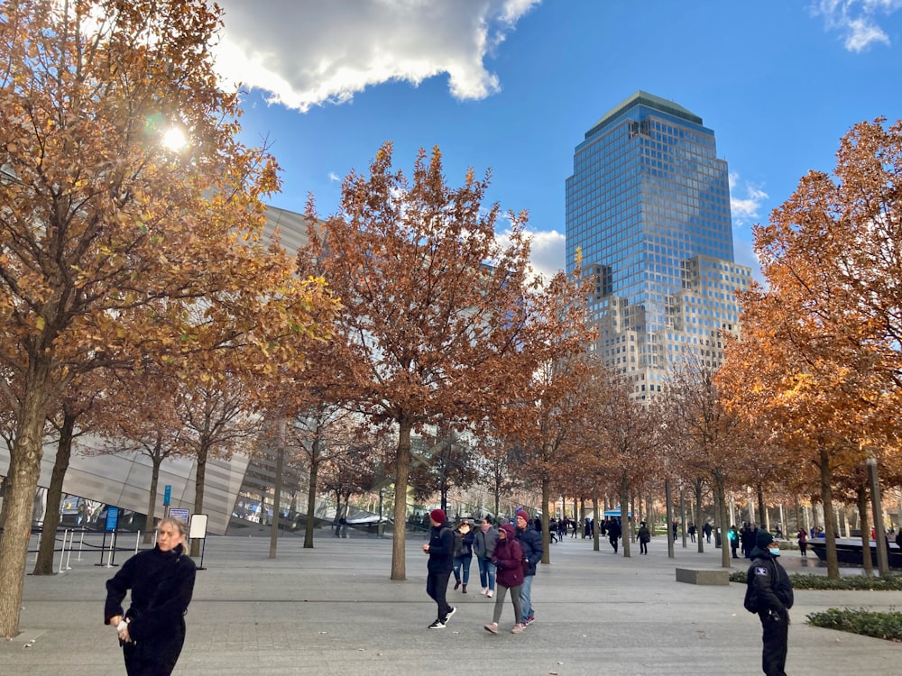 a group of people walking through a park next to tall buildings