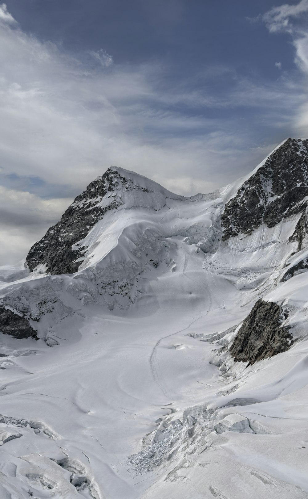 a mountain covered in snow under a cloudy sky