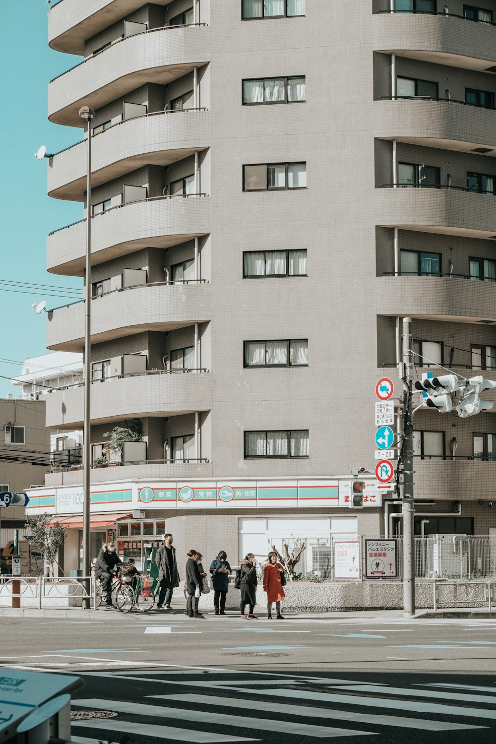 a group of people walking down a street next to a tall building