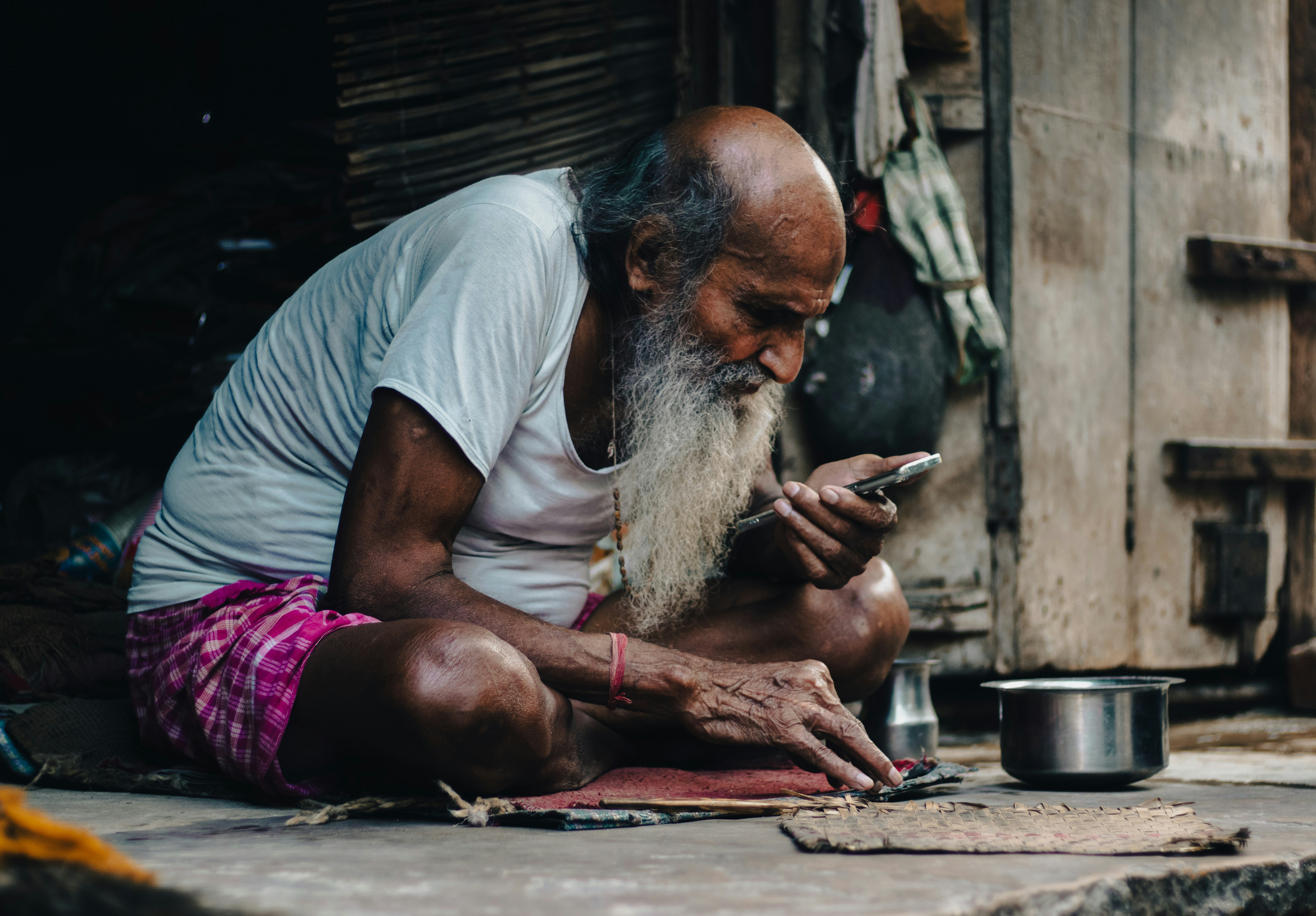 a man sitting on the ground looking at his cell phone