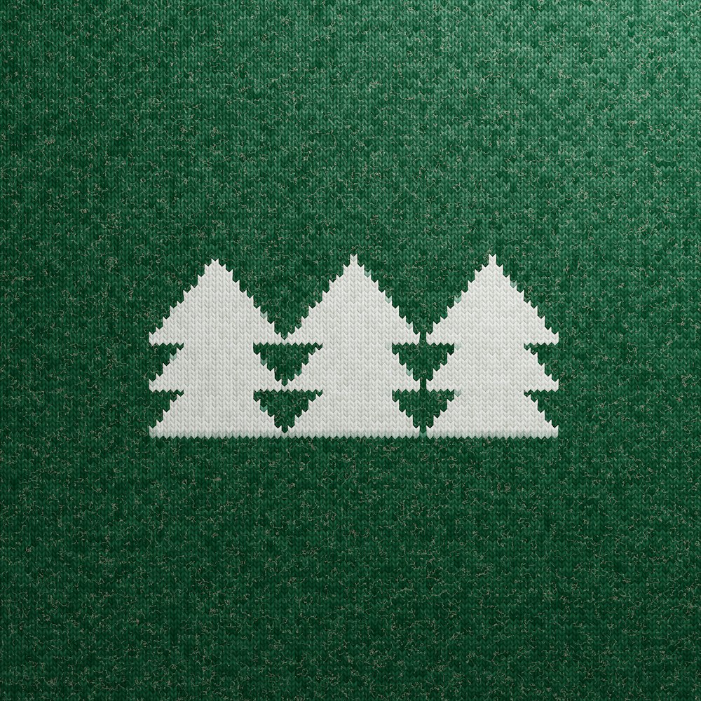 a cross stitch pattern of three trees on a green background