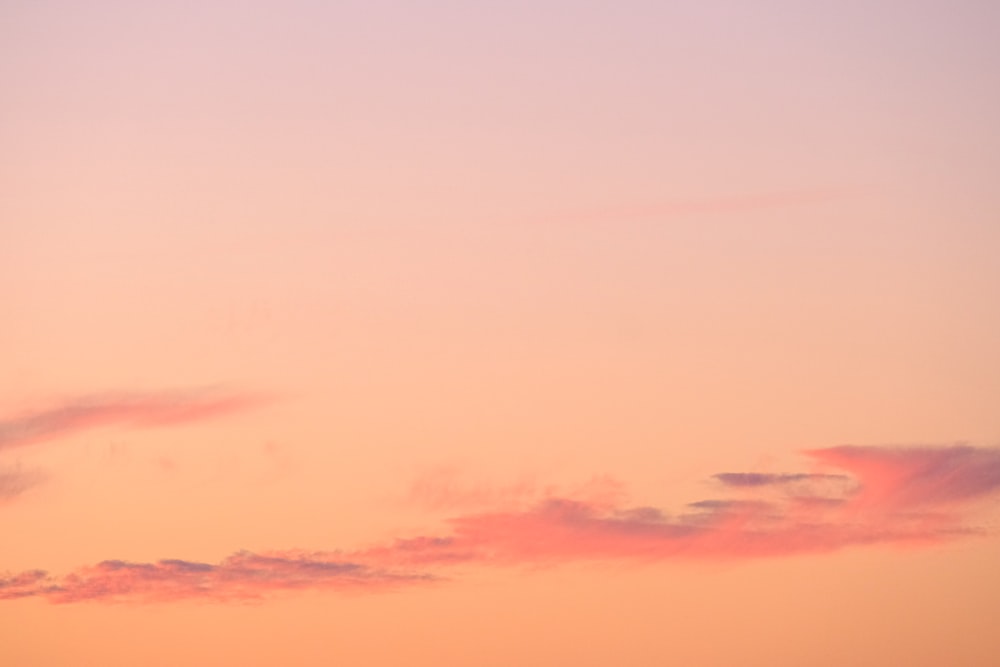 a plane flying in the sky at sunset