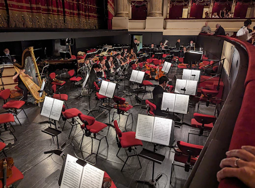 A cozy concert hall with musicians tuning their instruments before a game music performance.