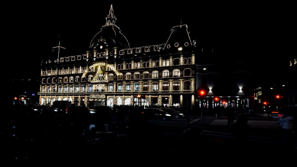 a building lit up at night with people walking around