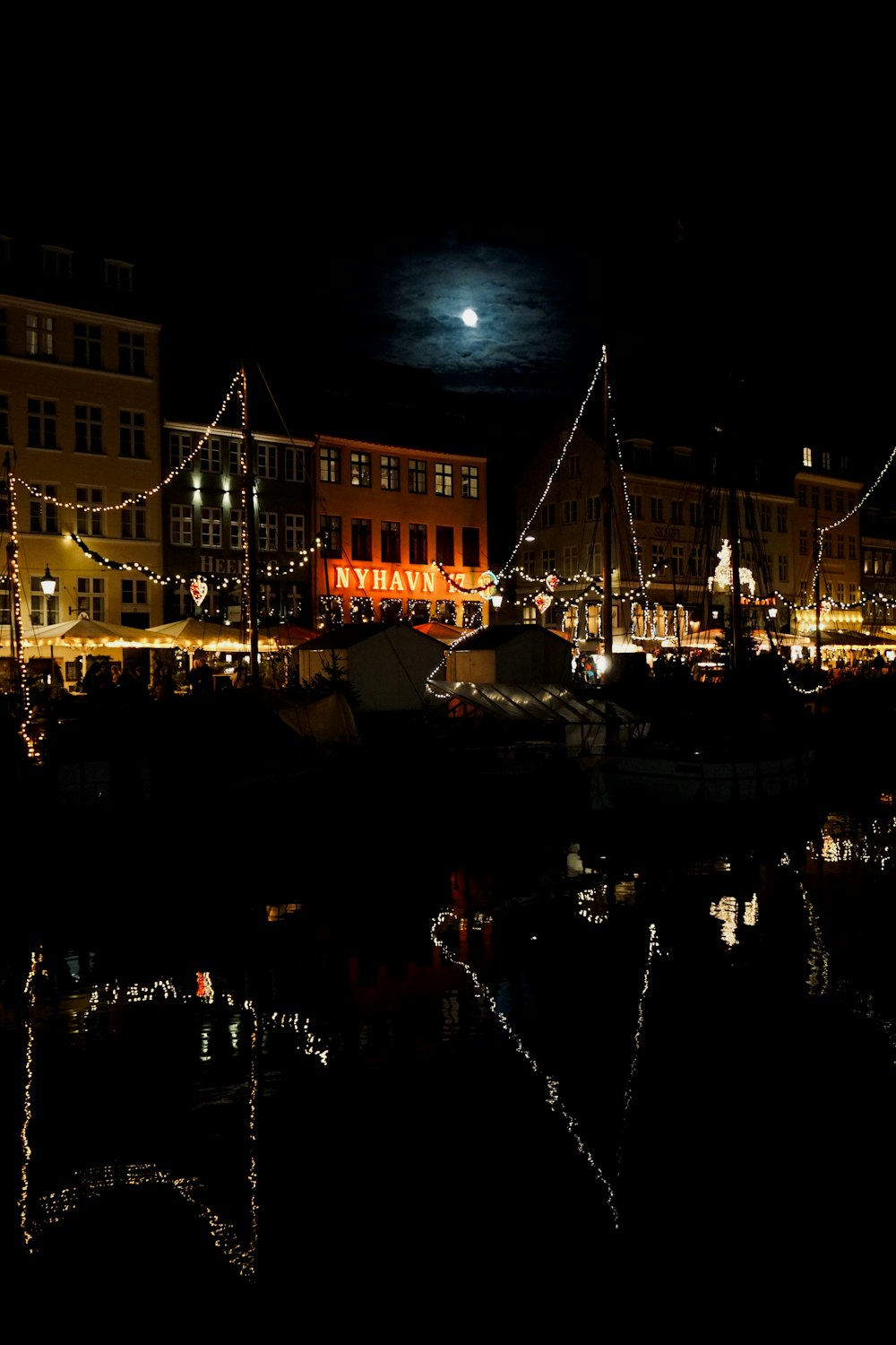 a night scene of a harbor with a full moon in the background
