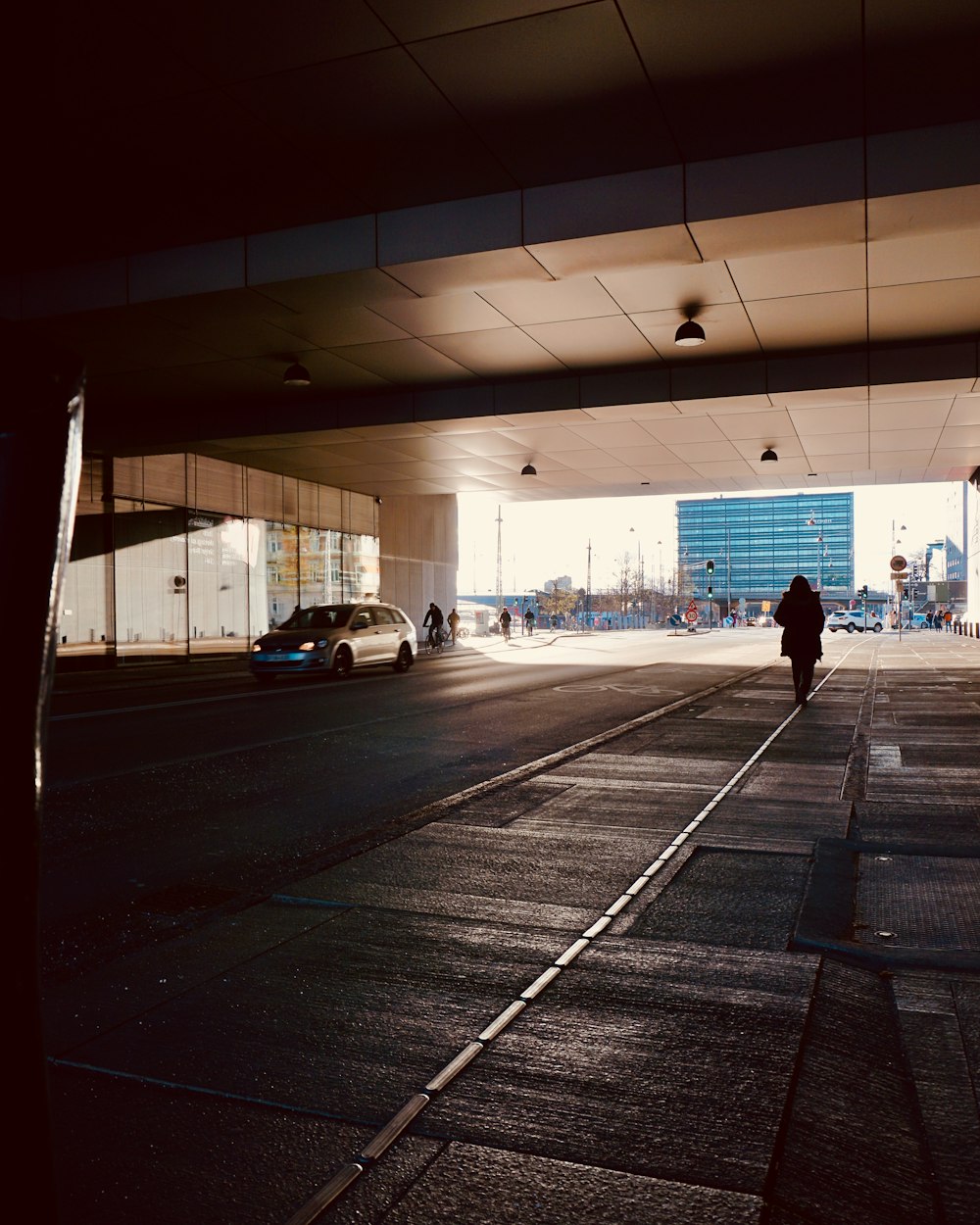 a person walking down a street under a bridge