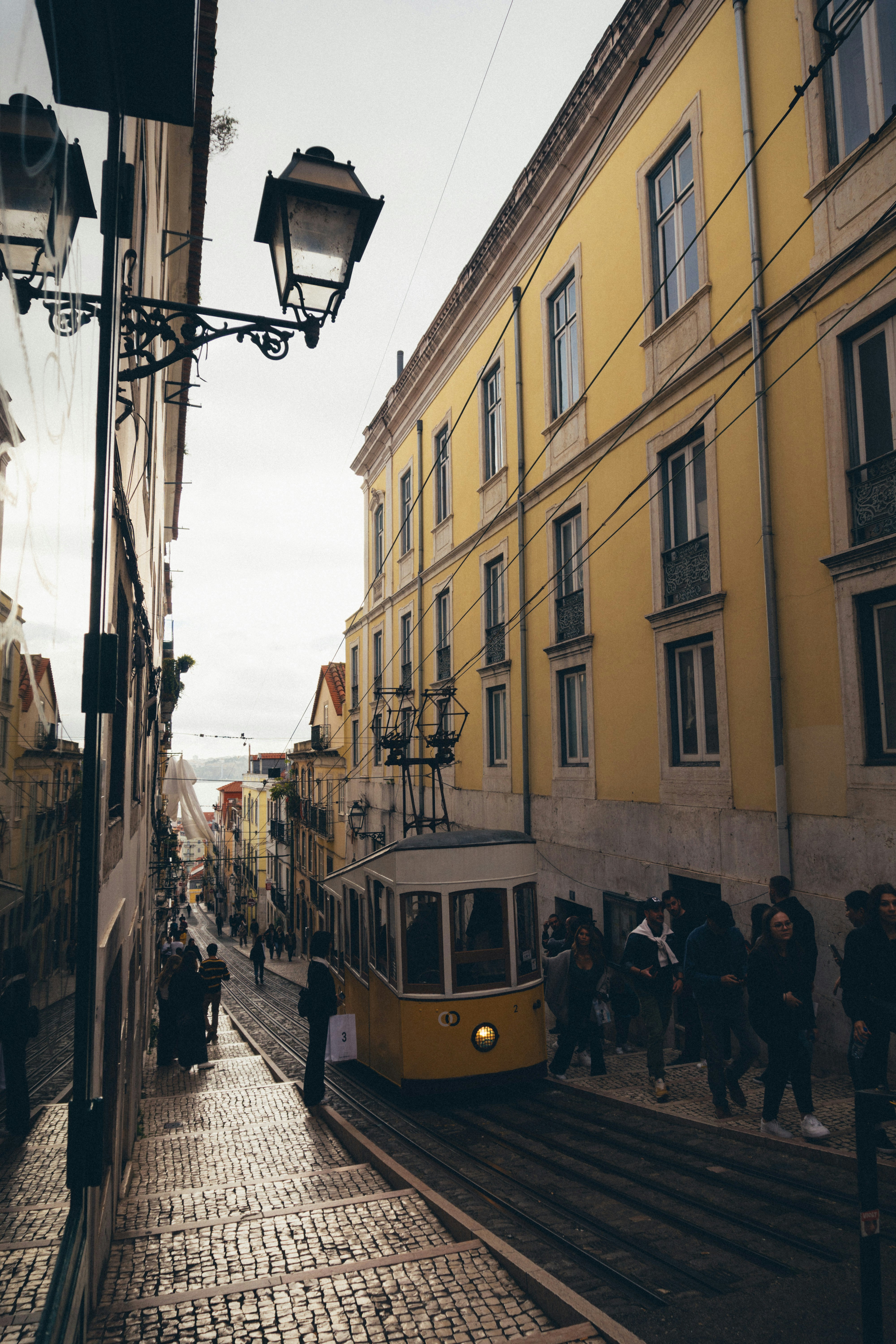 Eine gelbe Straßenbahn fährt eine Kopfsteinpflasterstraße hinunter