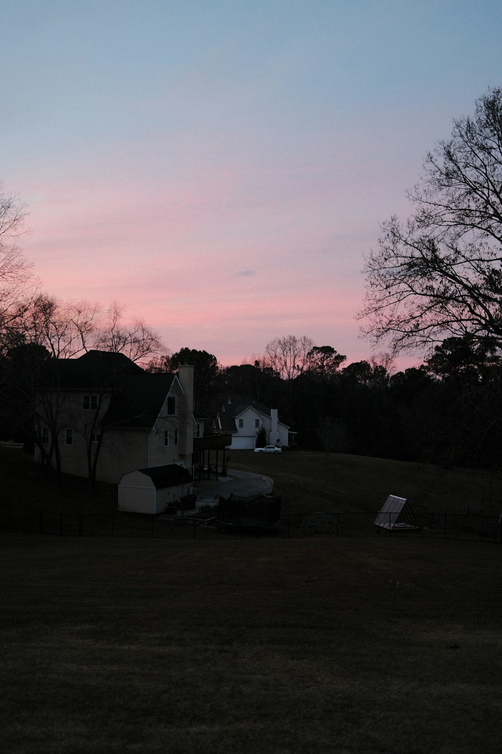 a pink and blue sky with a house in the foreground