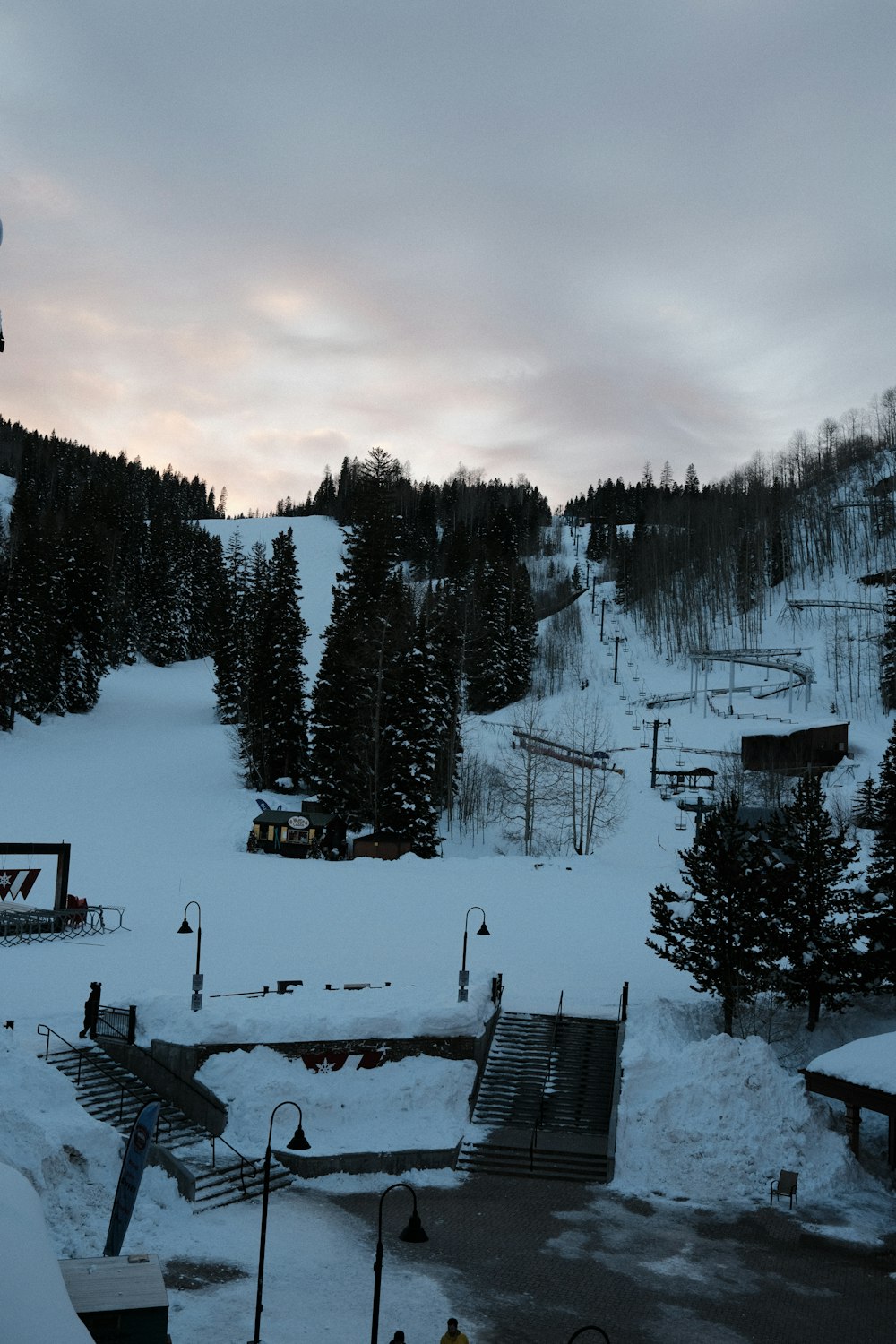 a snow covered ski slope with a ski lift in the background