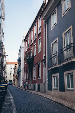 Traveler exploring narrow cobblestone street lined with colorful houses.